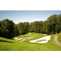 The fourth hole on the Threetops golf course at Treetops Resort features a small green with large bunkers left and right. 